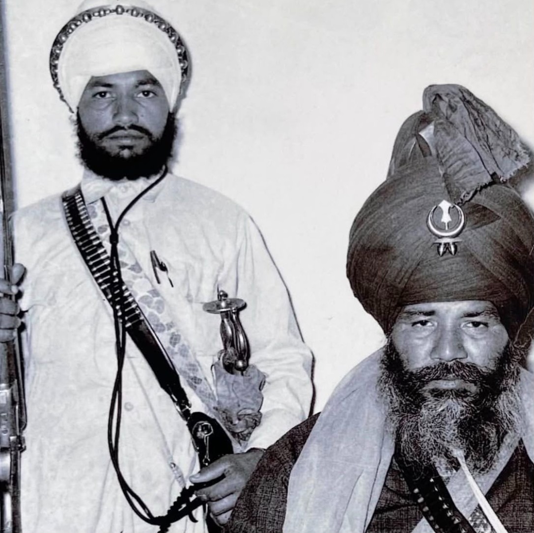 Two Nihung Singhs, one holding a rifle and kirpan